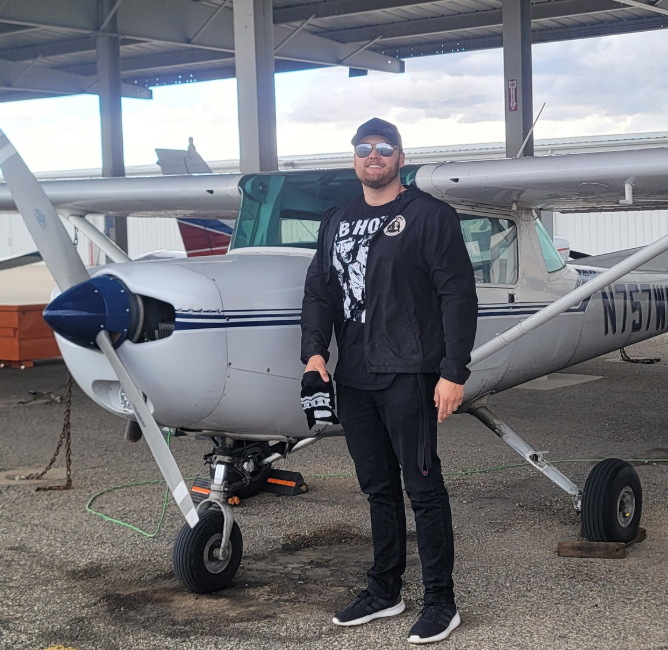 Aerotech student holding signed shirt by aircraft