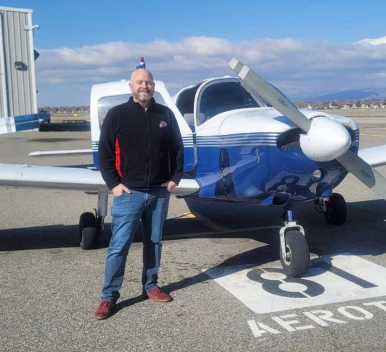 Aerotech student holding certificate by a Cessna