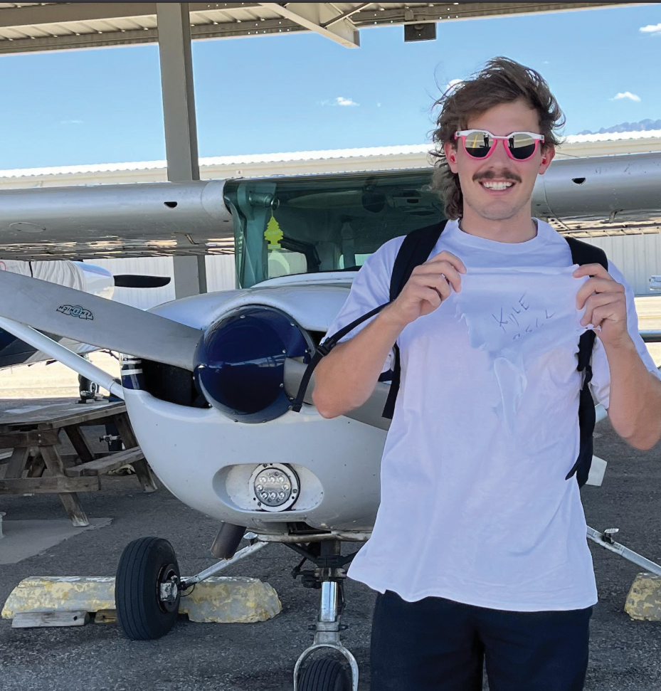 Aerotech student holding certificate by an aircraft